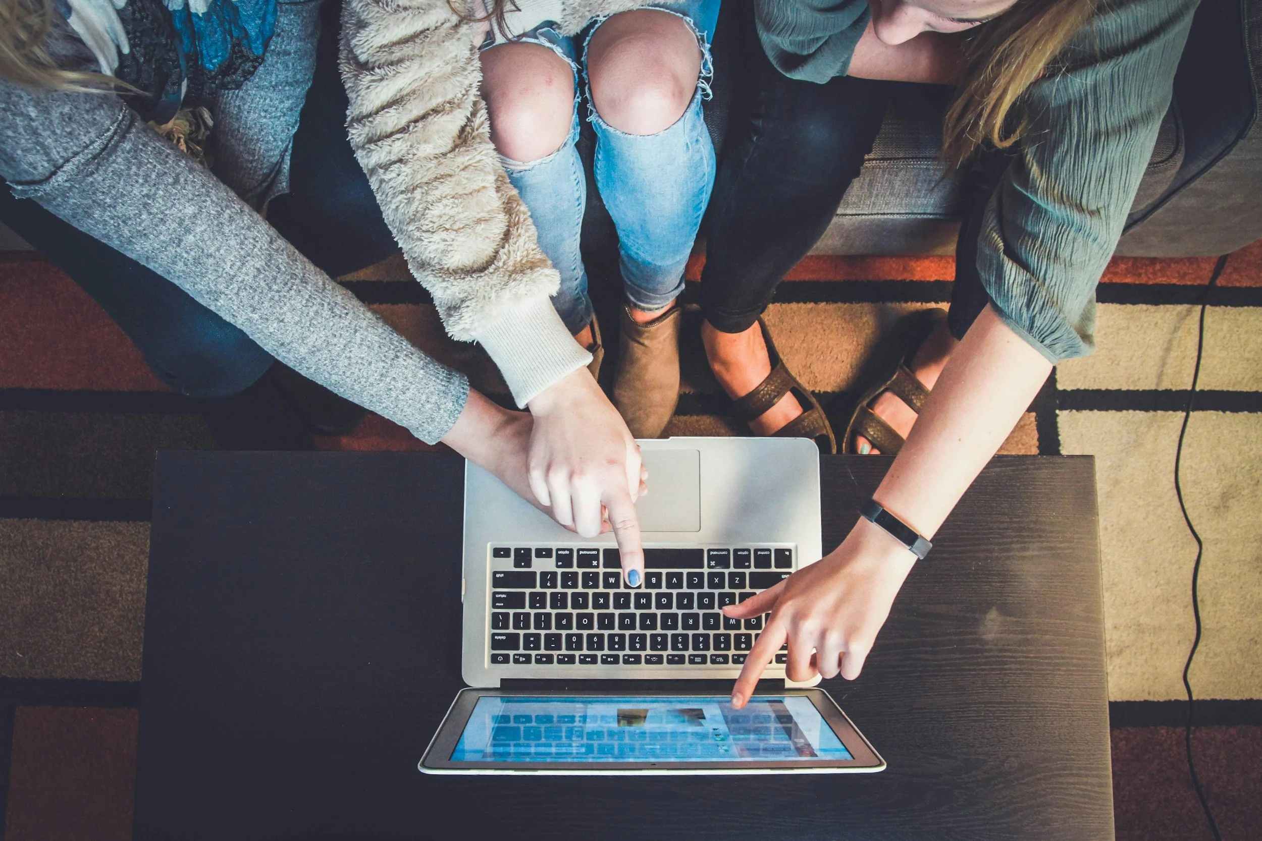 Two women looking at a laptop and tablet together
