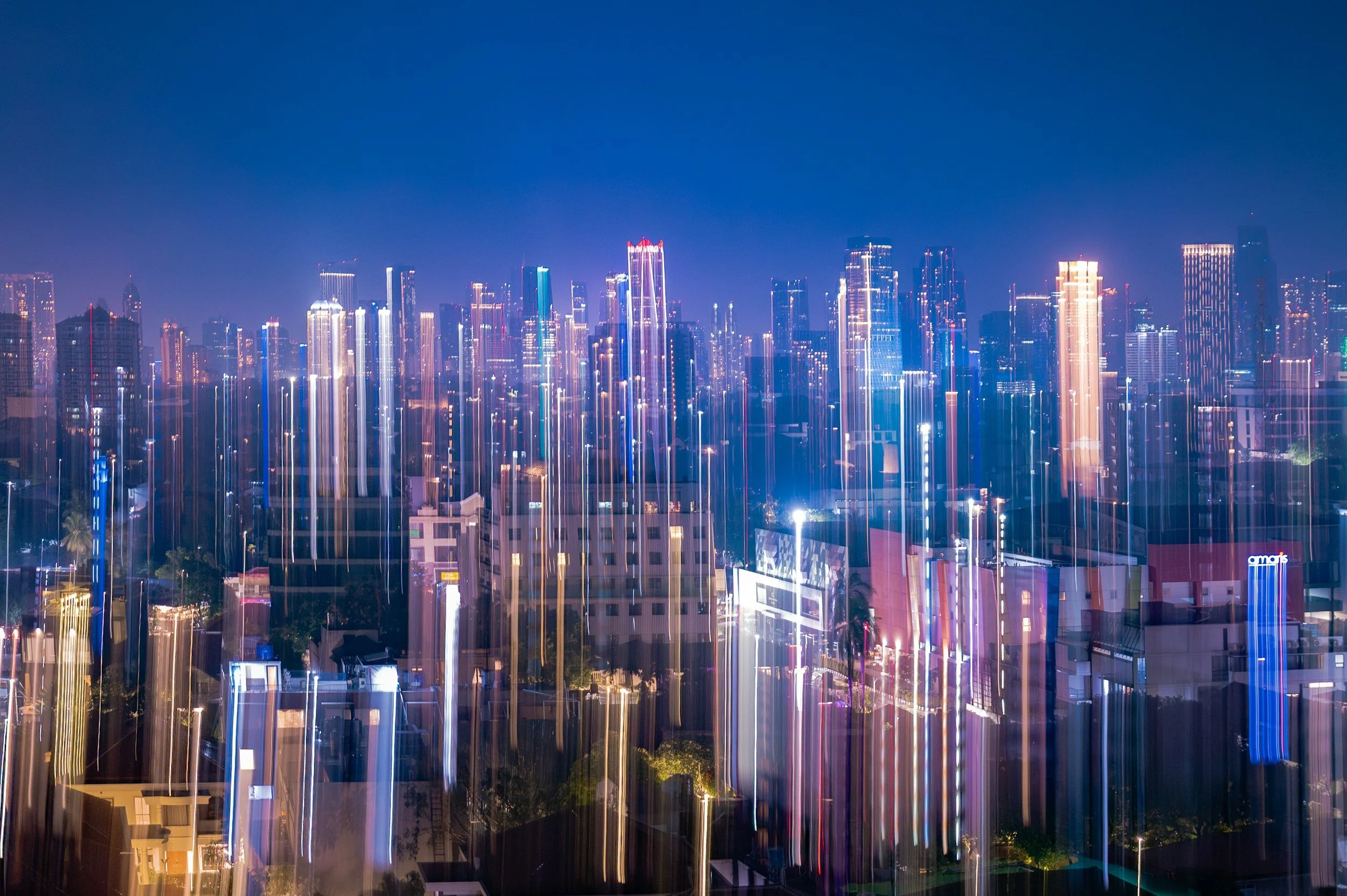 Night city skyline with tall buildings and colorful light streaks